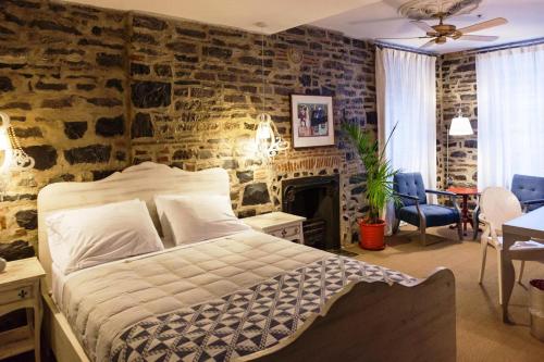 a bedroom with a bed and a stone wall at Auberge Place d'Armes in Quebec City