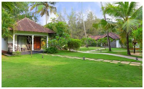 una casa con un césped verde delante de ella en Seclude Kerala, Marari Sands, en Mararikulam