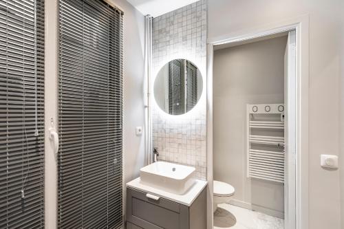 a white bathroom with a sink and a mirror at EMPLACEMENT PARFAIT - PARIS 7EME - BAIL MOBILITÉ in Paris