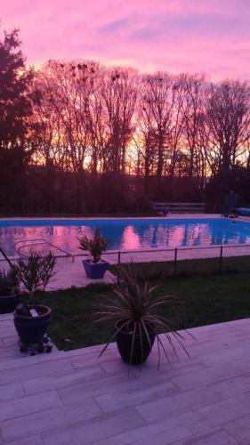 a swimming pool with a sunset in the background at Les loges in Parthenay