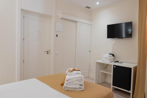 1 dormitorio con 1 cama y TV en la pared en CH Velarde, en Madrid