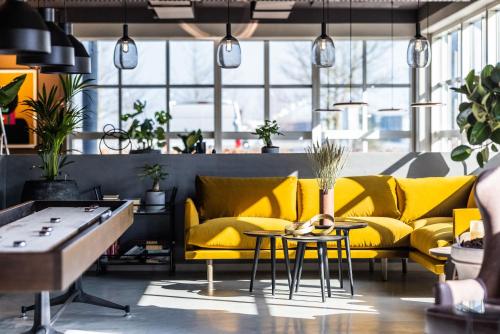 a room with yellow couches and tables and potted plants at Pier 5 Hotel in Aalborg