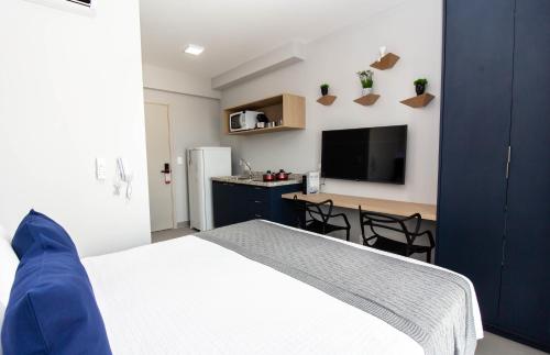 um quarto com uma cama e uma cozinha com uma televisão em 360 Brooklin em São Paulo