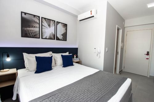 um quarto com uma grande cama branca com toques azuis em 360 Brooklin em São Paulo