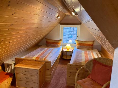 a attic room with two beds and a chair at Gästehaus am Bodensee in Immenstaad am Bodensee