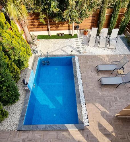 a swimming pool in a yard with some chairs at Shanti Paphos Holiday House in Paphos City