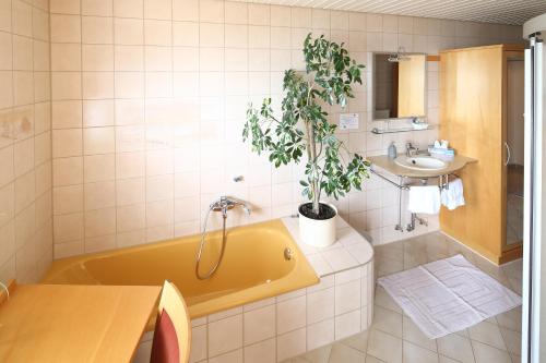 a bathroom with a yellow tub and a sink and a plant at Gästehaus am Bodensee in Immenstaad am Bodensee