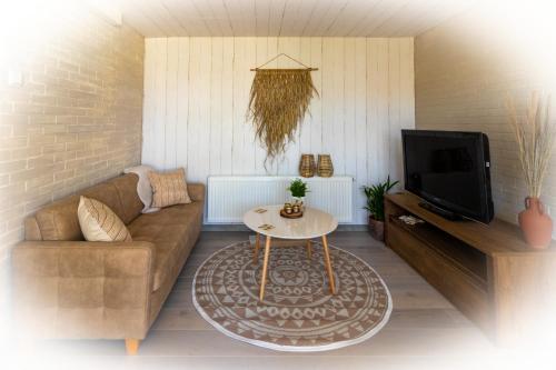 a living room with a couch and a table at Wellness Lodge aan de Braassem in Rijnsaterwoude