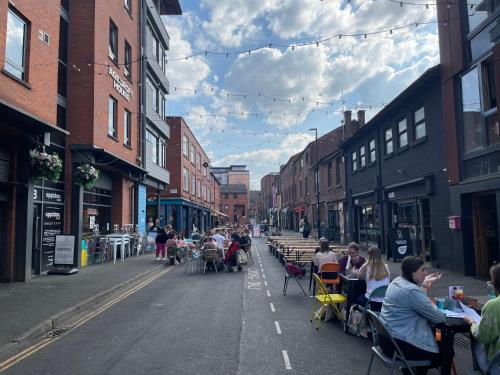 a street with people sitting at tables on an empty street at Quay Apartments Manchester in Manchester