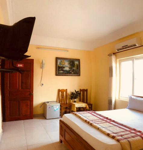 1 dormitorio con 1 cama, TV y ventana en Chapi Hotel, en Xóm Ðé