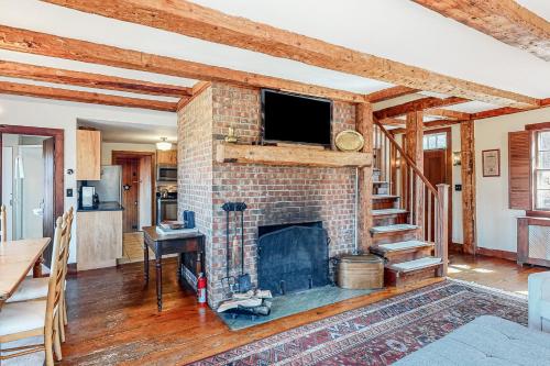a living room with a brick fireplace with a flat screen tv at Vermont Mountain Farmhouse in Ludlow