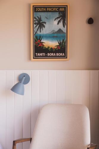 a picture hanging on a wall with a chair and a lamp at Øko Villa in Juquei
