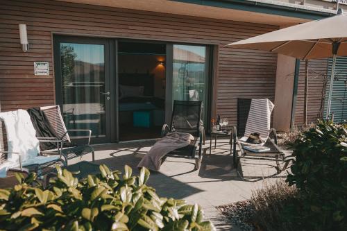 eine Terrasse mit 2 Stühlen und einem Sonnenschirm in der Unterkunft Winkel Art Hotel in Gamlitz
