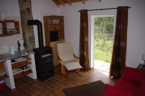 a living room with a chair and a stove at Monte da Gravita in Ribeira do Salto