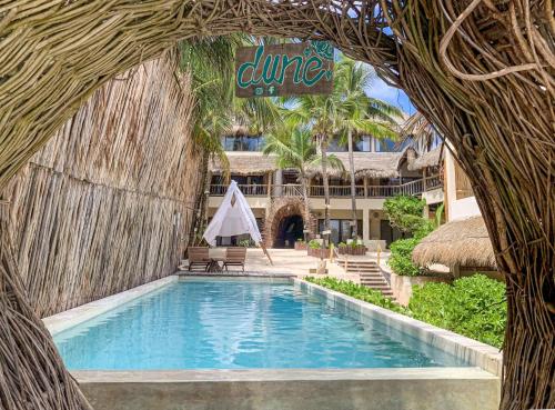 a swimming pool at a resort with a resort sign at Dune Boutique Hotel located at the party zone in Tulum