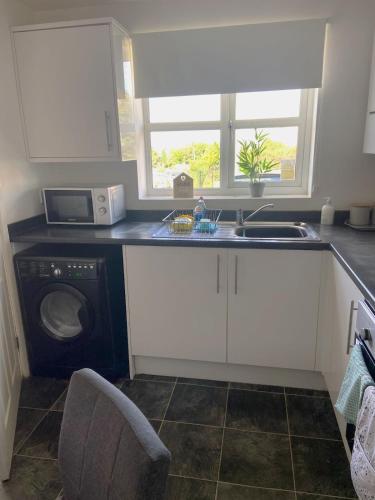 a kitchen with a sink and a microwave and a dishwasher at Kirkby House, 3 bedroom, sleeps up to 7 with sofa bed, holiday, corporate, contractor stays in Kirkby in Ashfield