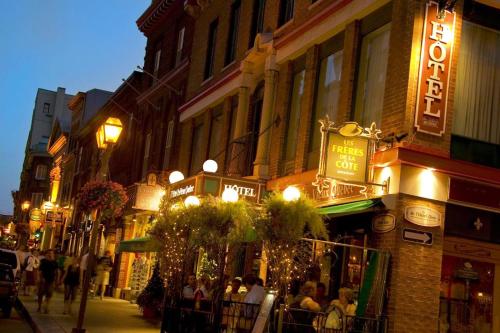 a street with people sitting outside a restaurant at night at Hotel du Vieux Quebec in Quebec City