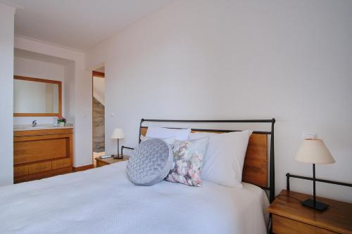 a bedroom with a white bed with a chair on it at Casa De Igarei in Igarei