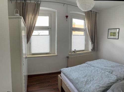 ein Schlafzimmer mit zwei Fenstern und einem Bett darin in der Unterkunft Ferienwohnung Am Anger in Naumburg
