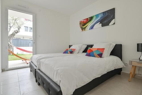 une chambre blanche avec un grand lit et une fenêtre dans l'établissement T4 NEUF - JARDIN-TERRASSE ET PISCINE – ACCÈS DIRECT PLAGES ET CENTRE VILLAGE – App C 12, à Saint-Cyr-sur-Mer