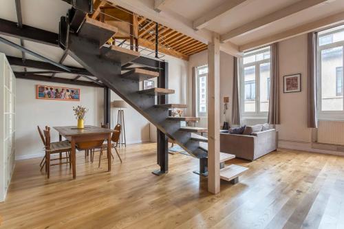 a living room and dining room with a staircase in a loft at Le Tisserand - Superbe Canut pentes Croix Rousse in Lyon
