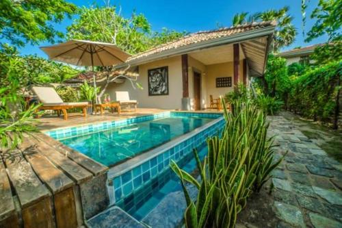 einen Pool vor einem Haus mit Sonnenschirm in der Unterkunft NIKARA Luxury Beach House in Tissamaharama