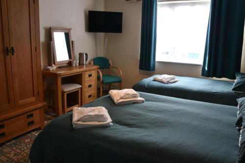a room with two beds and a desk and a mirror at Dinorben Arms Hotel in Amlwch