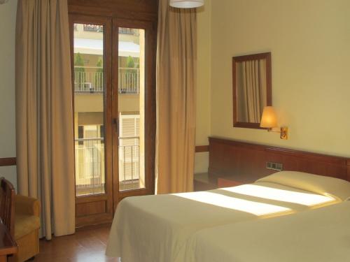 a bedroom with a bed and a window with a balcony at Hotel Europa in Girona