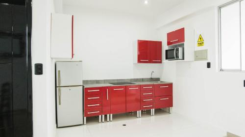 a kitchen with red cabinets and a refrigerator at Hotel Boutique Papagayo in Tarapoto