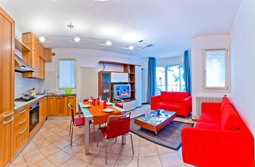 cocina y sala de estar con sillas rojas y mesa en Residence Caravelle, en Caorle