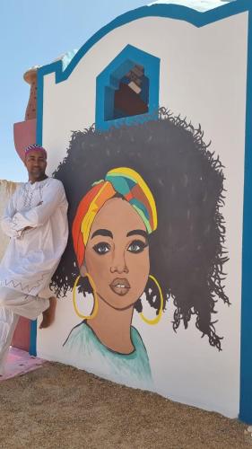 a man standing next to a painting of a black woman at malindy KA ماليندى كا in Aswan