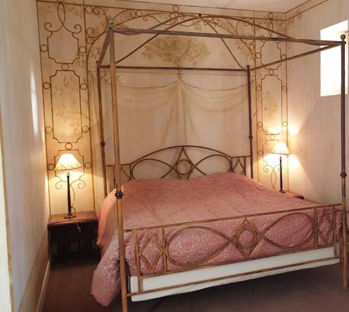 a bedroom with a canopy bed with two lamps at La Villa des Arts in Savigné-lʼÉvêque