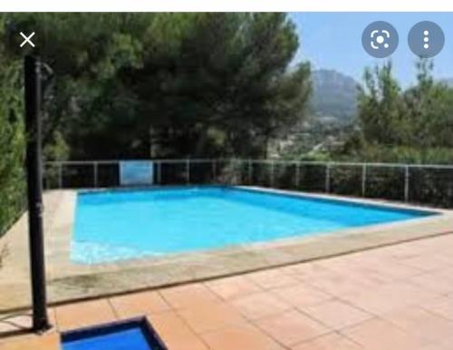 une grande piscine bleue entourée d'une clôture. dans l'établissement LA MAISON DE DOMS avec JACUZZI et vue mer, à Cassis