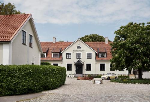 uma casa branca com um carro estacionado em frente dela em Hammenhögs gästgivaregård em Hammenhög