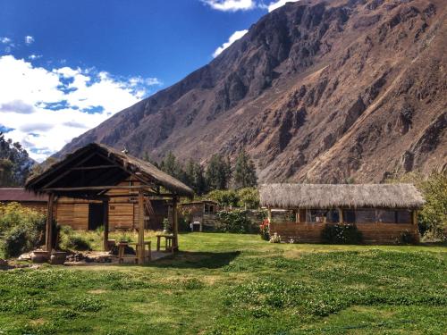 a cabin in a field with a mountain in the background at El Albergue Ollantaytambo in Ollantaytambo