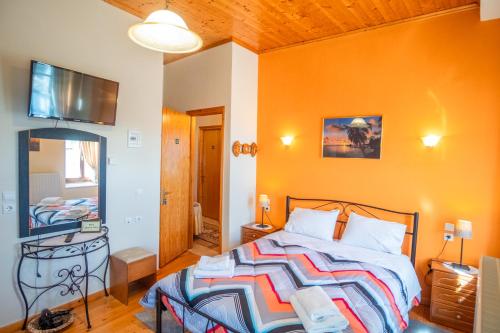 a bedroom with a bed with an orange wall at Gkoura hotel in Sirako