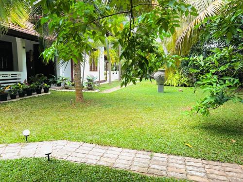a yard with a stone path and trees and a house at Krishan Villa in Negombo