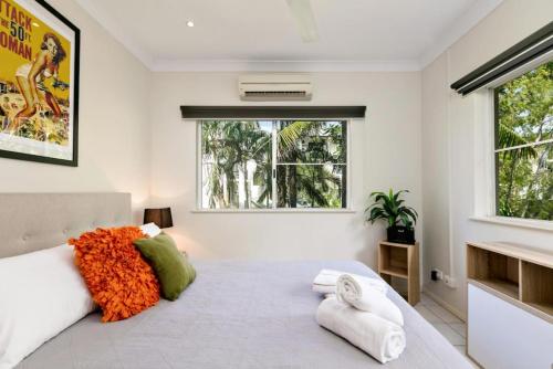 um quarto branco com uma cama grande com almofadas laranja em Tiki Dreams - With A Large Breezy Balcony em Westcourt