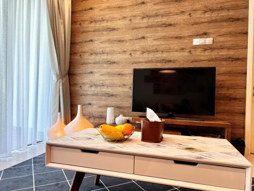 a living room with a tv and a table with fruit at Deco Home @ Imago The Loft in Kota Kinabalu