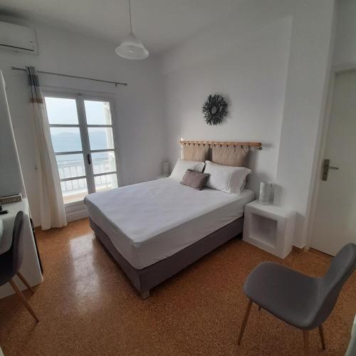 a white bedroom with a bed and a chair at Flora Rooms & Apartments in Naousa