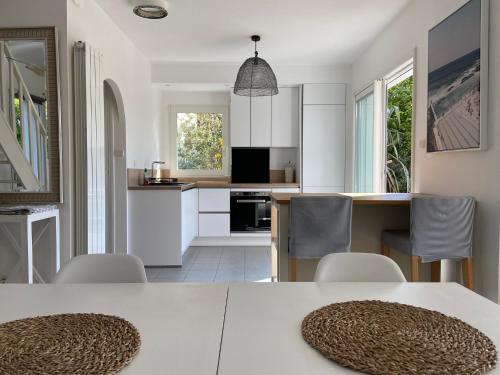 une cuisine avec des armoires blanches et une table et des chaises dans l'établissement Maison architecte Bois du Kador à Morgat (accès WIFI) Crozon Morgat, à Crozon