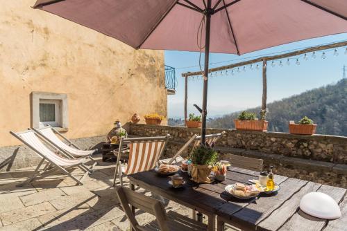 a table with an umbrella and chairs on a patio at Corte Paganini Casa Vacanze in Riccò del Golfo di Spezia