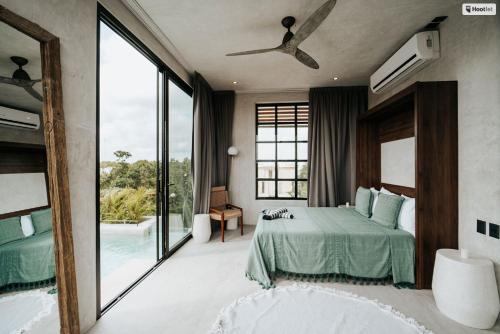 een slaapkamer met een groen bed en een groot raam bij Kings Mansion for 26 guests! in Tulum