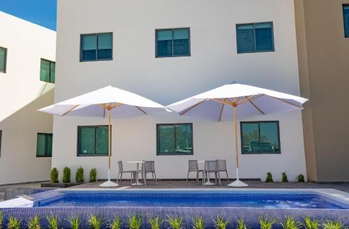 two umbrellas and chairs next to a swimming pool at HM HOTEL EXPRESS in Colima