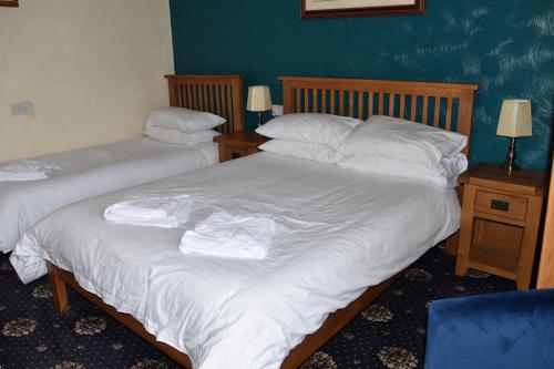 two beds in a room with white sheets and pillows at Dinorben Arms Hotel in Amlwch