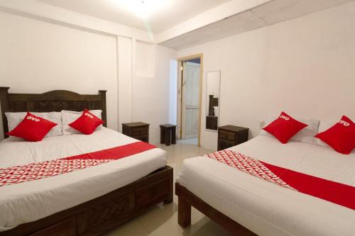two beds in a room with red pillows at OYO Hotel Punta Guadalupe, San Cristóbal de las Casas in San Cristóbal de Las Casas