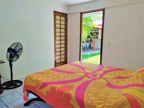 a bedroom with a bed and a fan and a window at MOOREA - Fare Te Utuafare in Hauru