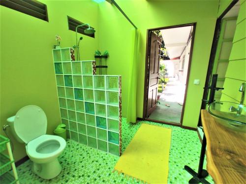 a green bathroom with a toilet and a mirror at MOOREA - Fare Te Utuafare in Hauru