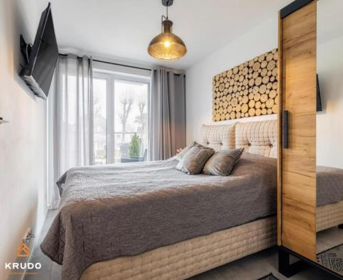 a bedroom with a large bed with a wooden headboard at Apartament Diva 12 in Mielno