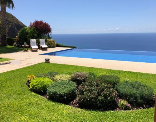 a yard with a swimming pool next to the ocean at Morning Star Villa in Arco da Calheta